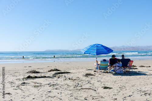 People sitting under bright blue striped umbrella