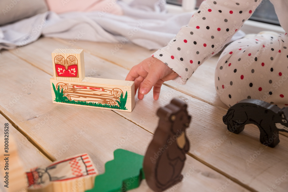 Obraz premium Colorful Animal Theme Urban Toys.child playing with toy ,made of wooden blocks on wooden texture floor indoors in his room. Concept of educational and developing toys for children. mini furniture toys
