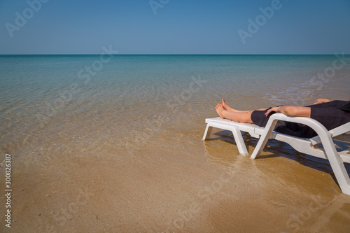 Fototapeta Naklejka Na Ścianę i Meble -  Vacation on tropical beach Woman's legs on the beach bed with clear ocean water