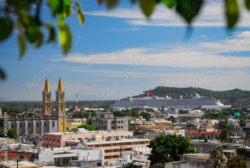 High vantage point of downtown Mazatlan with a large cruise ship docked at the harbor and an old church in the middle