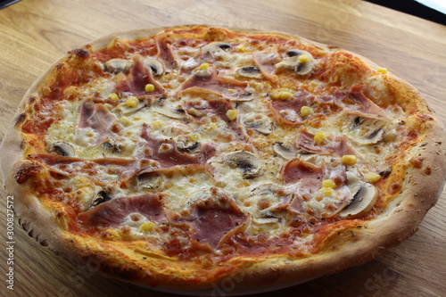 Calabrian pizza with ham, mushroom and cheese on a white plate.