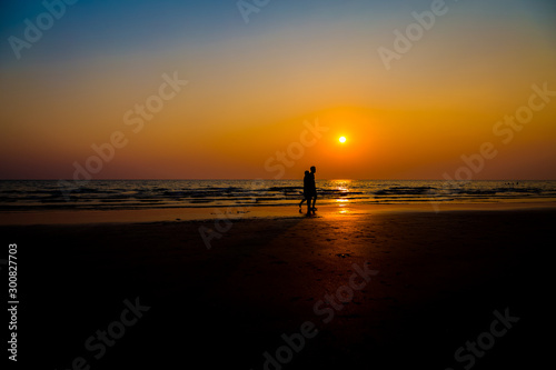 Siluate lovers and beach before sunset