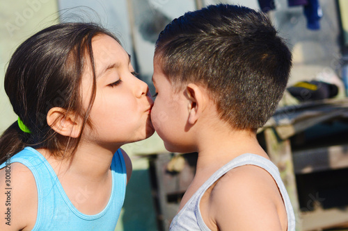 Tender portrait of little latin siblings kissing.