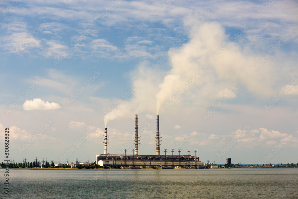 Thermal power station tall pipes with thick smoke reflected in lke water surface. Pollution of environment concept.