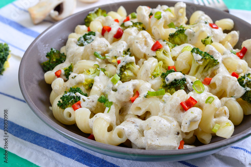 Cavatappi pasta with broccoli, red pepper and cream sauce in a bowl. Vegetarian dish. Delicious wholesome food. Proper nutrition.