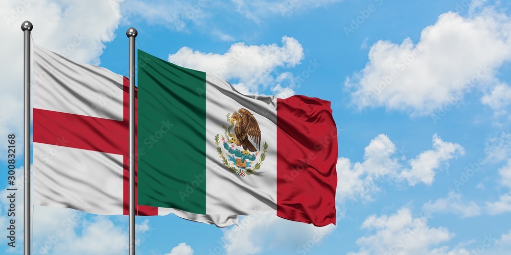 England and Mexico flag waving in the wind against white cloudy blue sky together. Diplomacy concept, international relations.