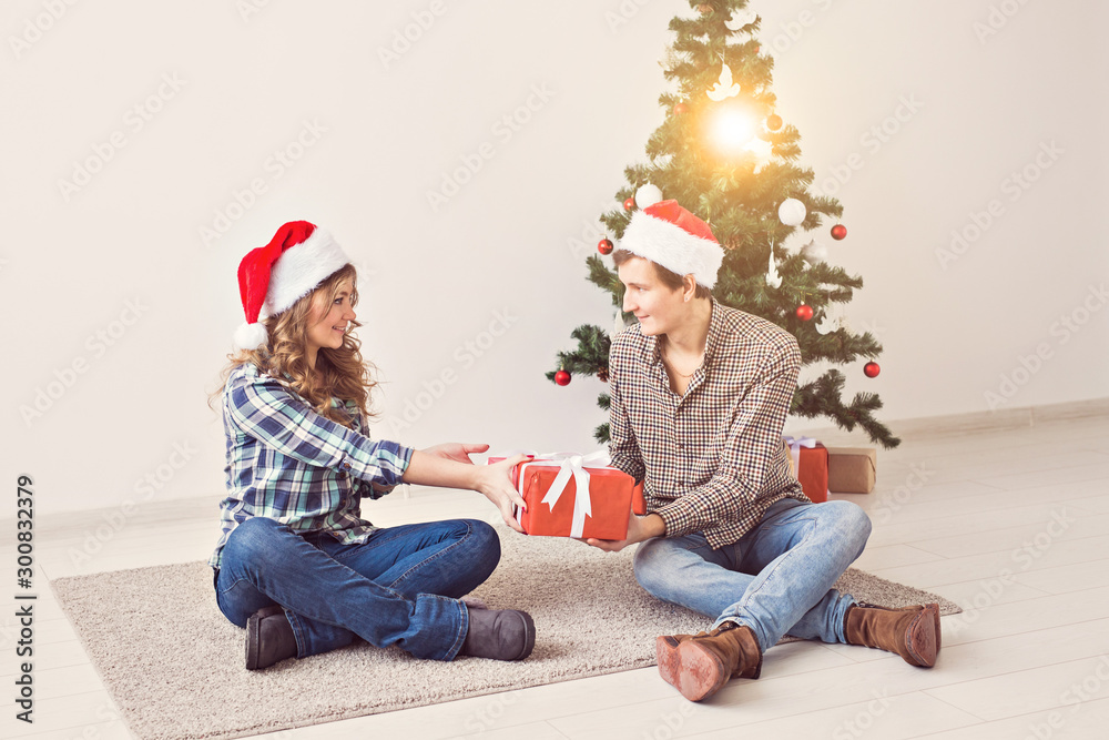 Holidays, christmas and family concept - Young happy couple opening gifts at home. Holidays, christmas and family concept - Young happy couple opening gifts at home.