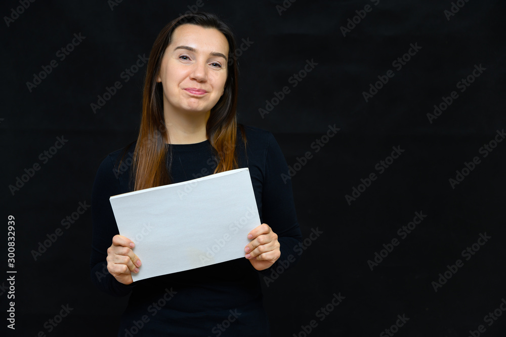 Portrait of an adult woman without makeup with clean skin, with long brown hair over her face on a black background. He stands in front of the camera in a black T-shirt, shows his hands emotions. Portrait of an adult woman without makeup with clean skin, with long brown hair over her face on a black background. He stands in front of the camera in a black T-shirt, shows his hands emotions.