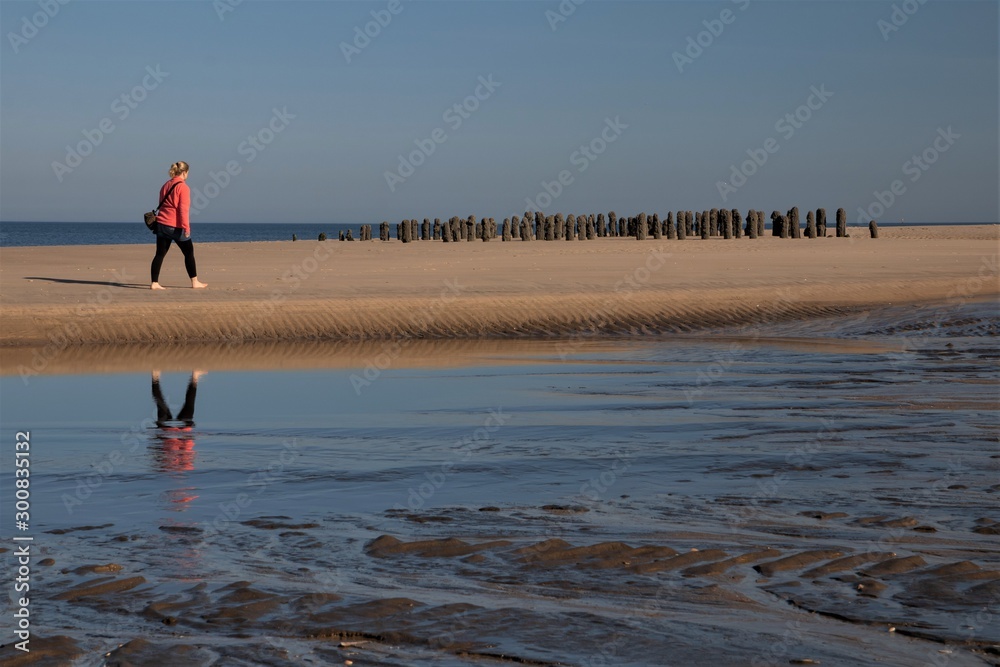 woman walking along the sandy beach by the sea
