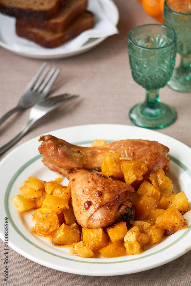 Baked chicken legs with pumpkin on a white plate Baked chicken legs with pumpkin on a white plate