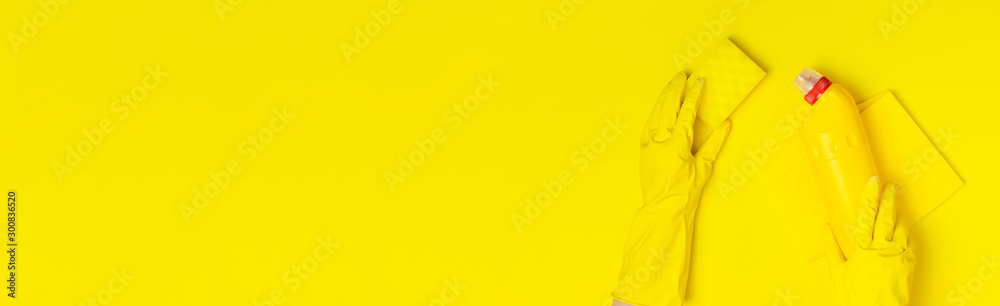 House cleaning concept. Women's hands in yellow rubber gloves, household chemicals, bleach, antibacterial gel, sponge, rags on yellow background. Flat lay top view copy space. Cleaning accessories House cleaning concept. Women's hands in yellow rubber gloves, household chemicals, bleach, antibacterial gel, sponge, rags on yellow background. Flat lay top view copy space. Cleaning accessories