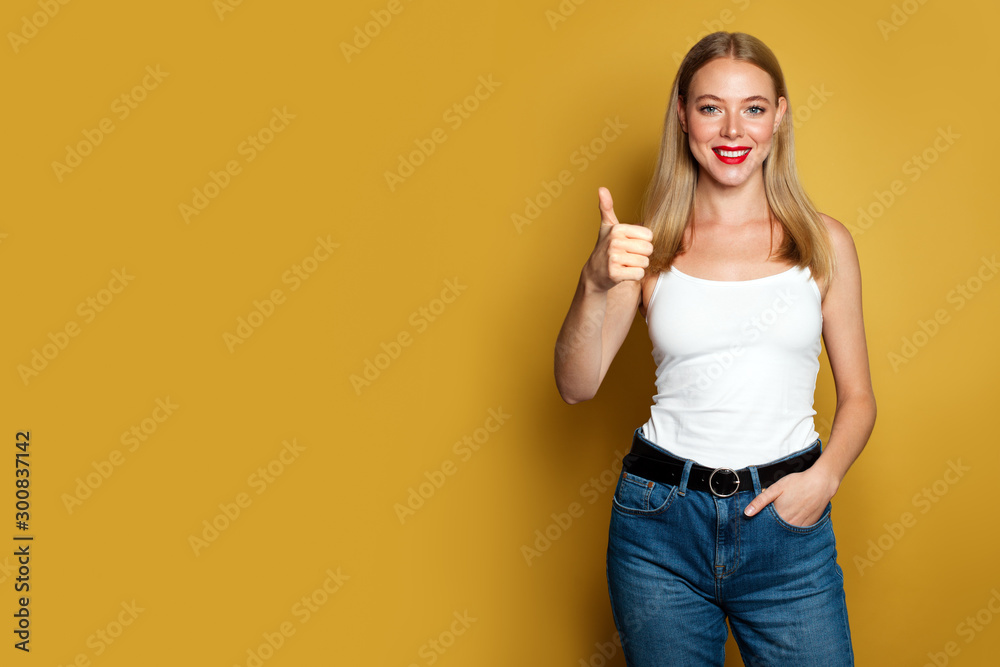 Happy young woman showing thumb up on yellow background. Positive emotion Happy young woman showing thumb up on yellow background. Positive emotion