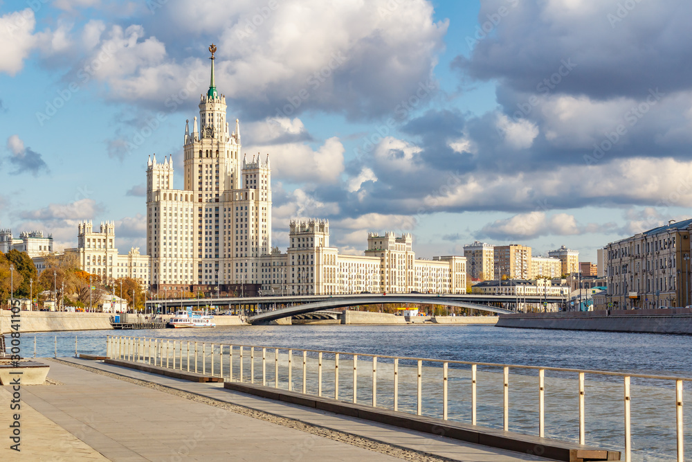 View of famous stalin skyscraper on Kotelnicheskaya Embankment against pier of cruise ships on Moskva River in sunny autumn day