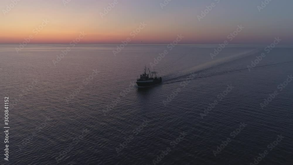 Fishing boat sailing on sea in summer night twilight after sunset aerial shot Fishing boat sailing on sea in summer night twilight after sunset aerial shot