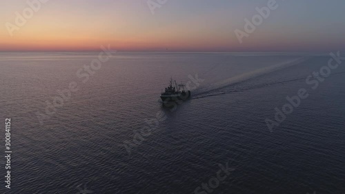 Fishing boat sailing on sea in summer night twilight after sunset aerial shot