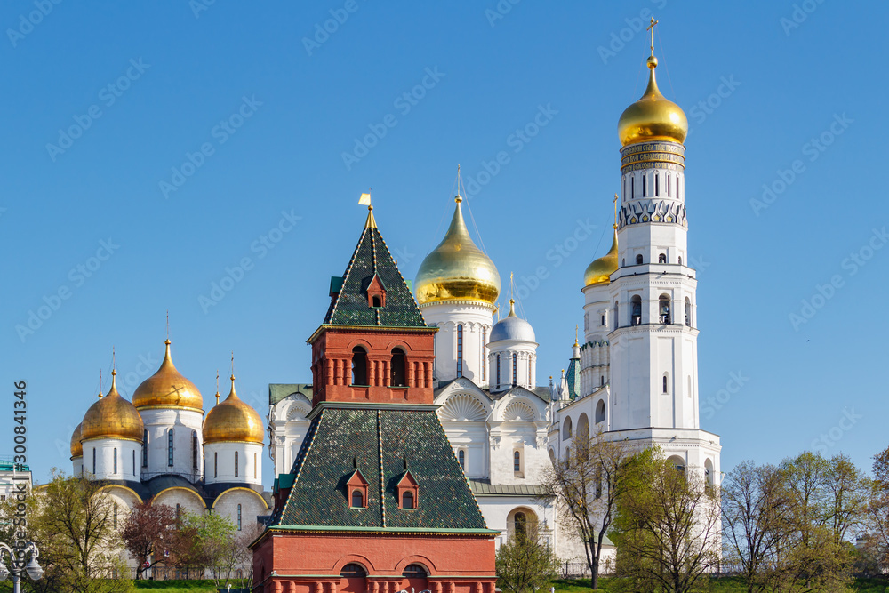 Orthodox churches with golden domes against tower of Moscow Kremlin in sunlight. Kremlin is a famous touristic landmark in Moscow center