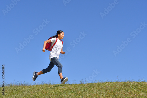 青空で走る小学生の女の子（ランドセル）