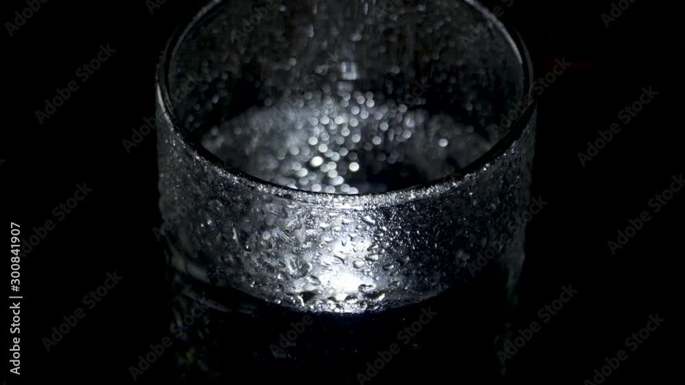 A wet glass of water spins in the dark and moves away A wet glass of water spins in the dark and moves away