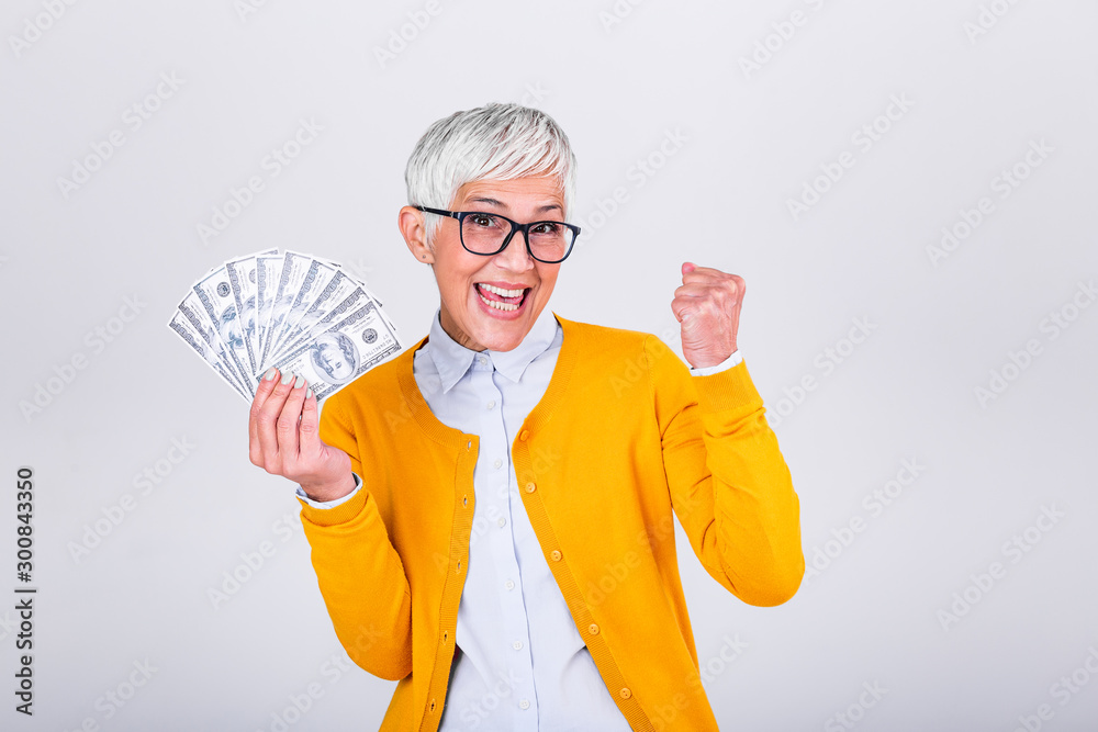 Beautiful senior lady holding a bunch of $100 bills with surprised facial expression. Mature woman winning money. Finances and people concept, senior woman holding hundreds of dollar money banknotes Beautiful senior lady holding a bunch of $100 bills with surprised facial expression. Mature woman winning money. Finances and people concept, senior woman holding hundreds of dollar money banknotes