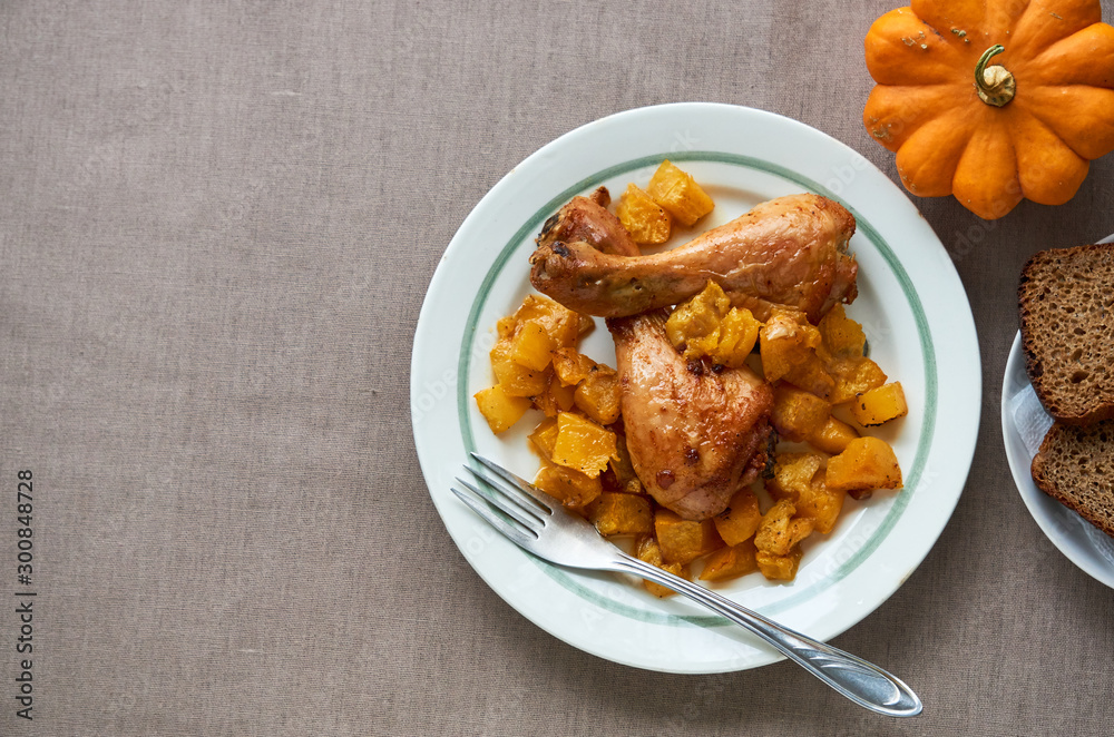 Baked chicken legs with pumpkin on a white plate Baked chicken legs with pumpkin on a white plate