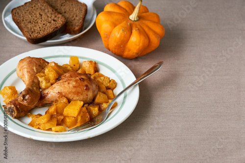 Baked chicken legs with pumpkin on a white plate