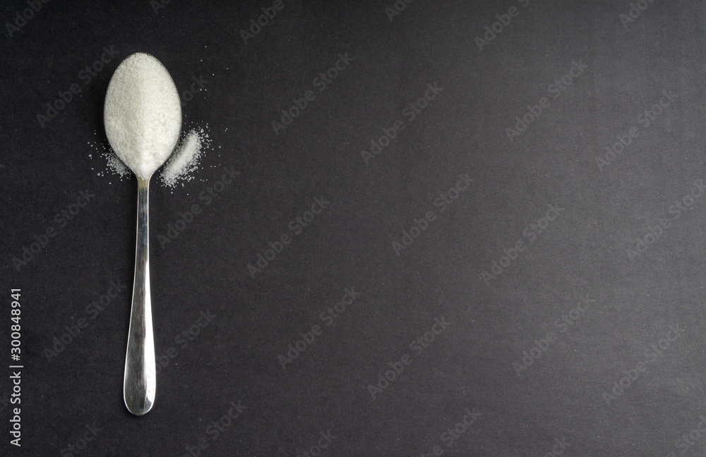 Minimalist flat lay composition sugar and spoon on the dark background. Medical, Healthcare and Diabetes Concept. Top view and selective focus. Minimalist flat lay composition sugar and spoon on the dark background. Medical, Healthcare and Diabetes Concept. Top view and selective focus.