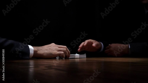 Businessman giving money to partner in dark room after making secret deal, bribery and corruption concepts photo