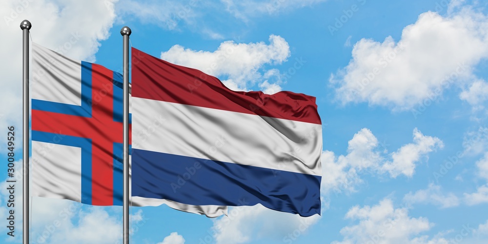Faroe Islands and Netherlands flag waving in the wind against white cloudy blue sky together. Diplomacy concept, international relations.