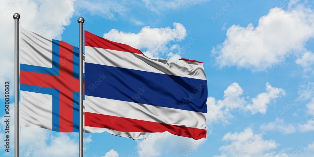 Faroe Islands and Thailand flag waving in the wind against white cloudy blue sky together. Diplomacy concept, international relations.