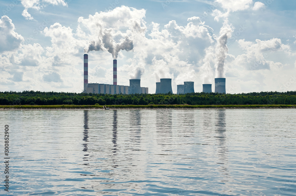 Coal-fired  power station mirroring in water, with steam billowing from high chimneys in Poland