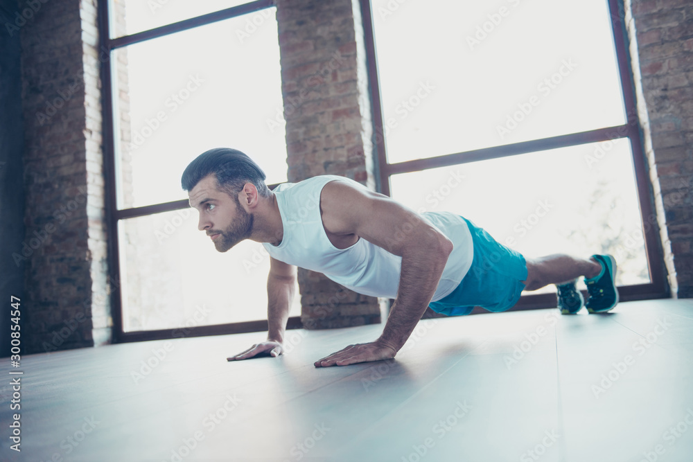 Profile photo of macho sportsman guy do push ups plank hands leaning floor determined trainer sportswear tank-top shorts sneakers training house studio windows indoors Profile photo of macho sportsman guy do push ups plank hands leaning floor determined trainer sportswear tank-top shorts sneakers training house studio windows indoors