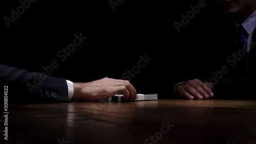 Businessman rejecting money given by his partner on the table in dark room for anti bribery and corruption concepts photo