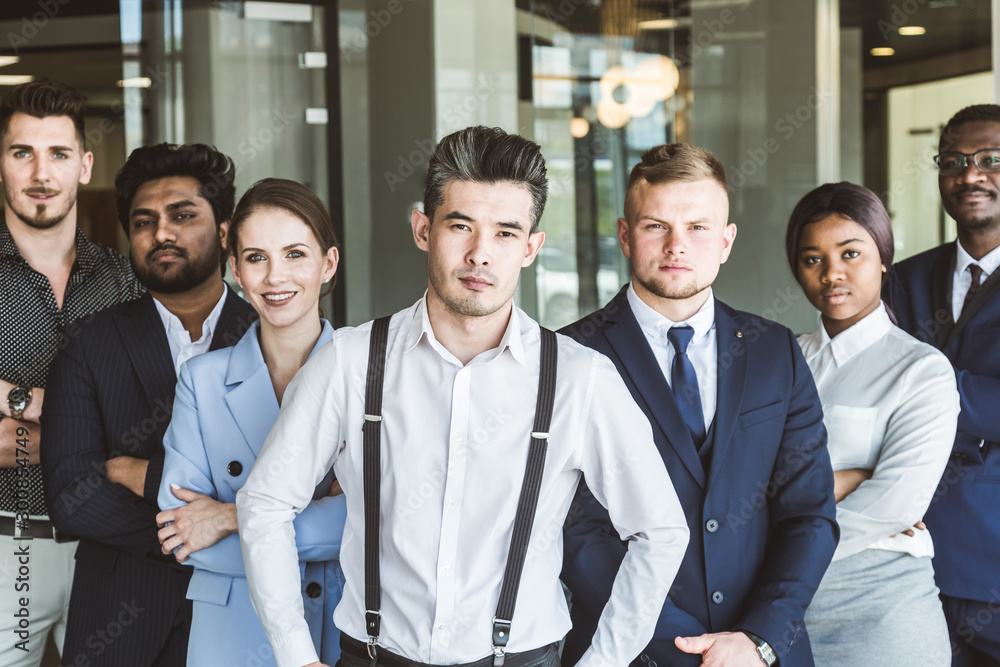 A team of young businessmen stand shoulder to shoulder, working and communicating together in an office. Corporate businessteam and manager in a meeting.