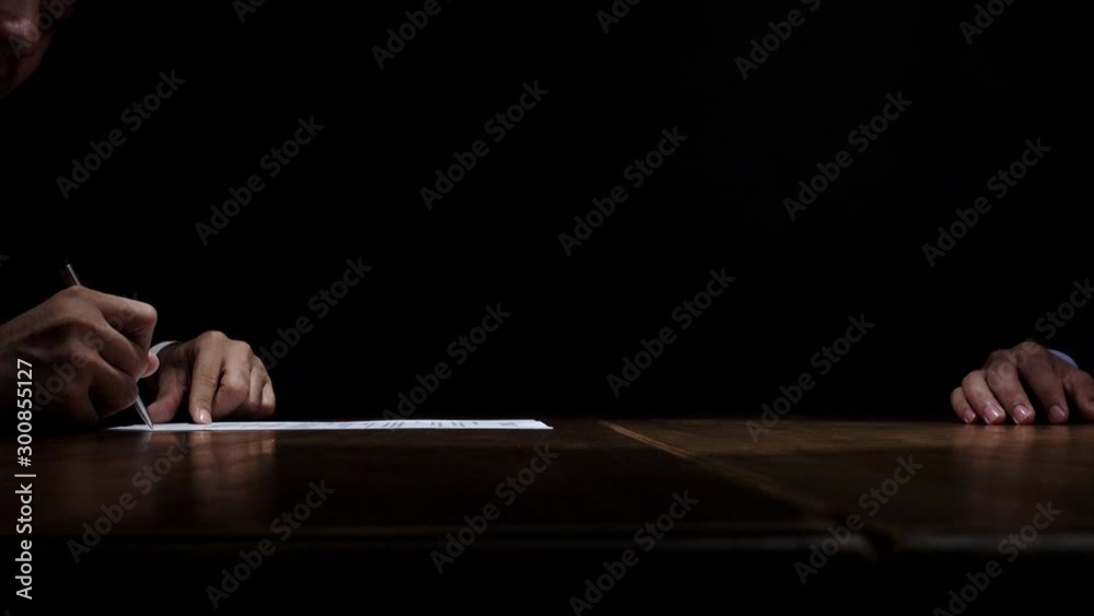 Businessman receiving bribe money from partner after making a deal and signing confidential contract paper in dark room 