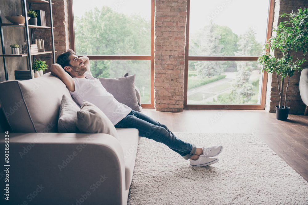 Profile photo of mixed race guy sitting cozy sofa holding hands behind head relaxing homey weekend mood looking dreamy new repair wear casual outfit flat loft living room indoors Profile photo of mixed race guy sitting cozy sofa holding hands behind head relaxing homey weekend mood looking dreamy new repair wear casual outfit flat loft living room indoors
