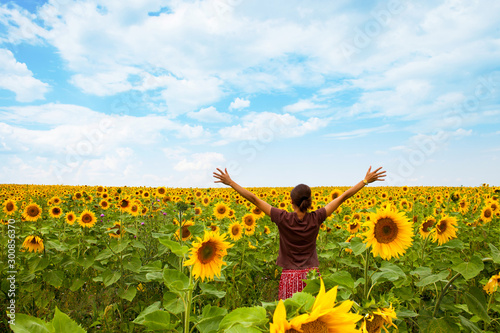 Young woman in a sunflower field over blue sky