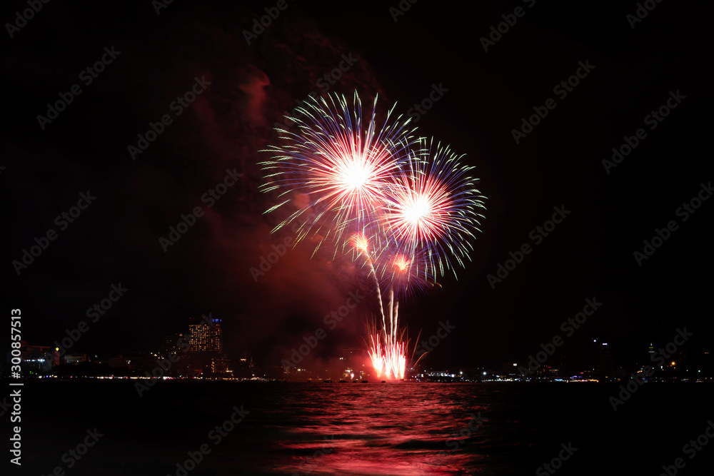 Fireworks over sea with city night on background. Festive colorful fireworks celebration in night sky. Fireworks over sea with city night on background. Festive colorful fireworks celebration in night sky.