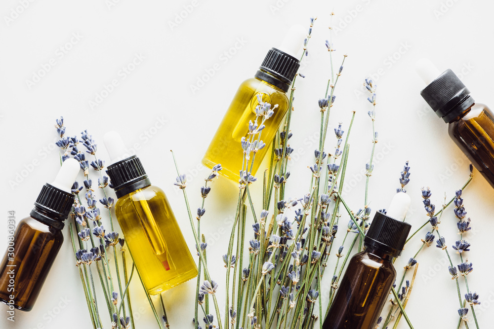 Foto top view of dry lavender twigs with flowers and bottles with natural oil on whit