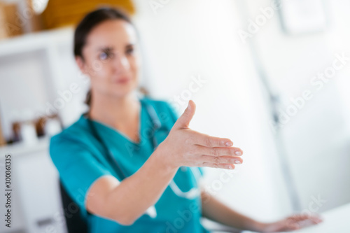 Young female doctor in medical office. Beautiful female doctor handshaking. 