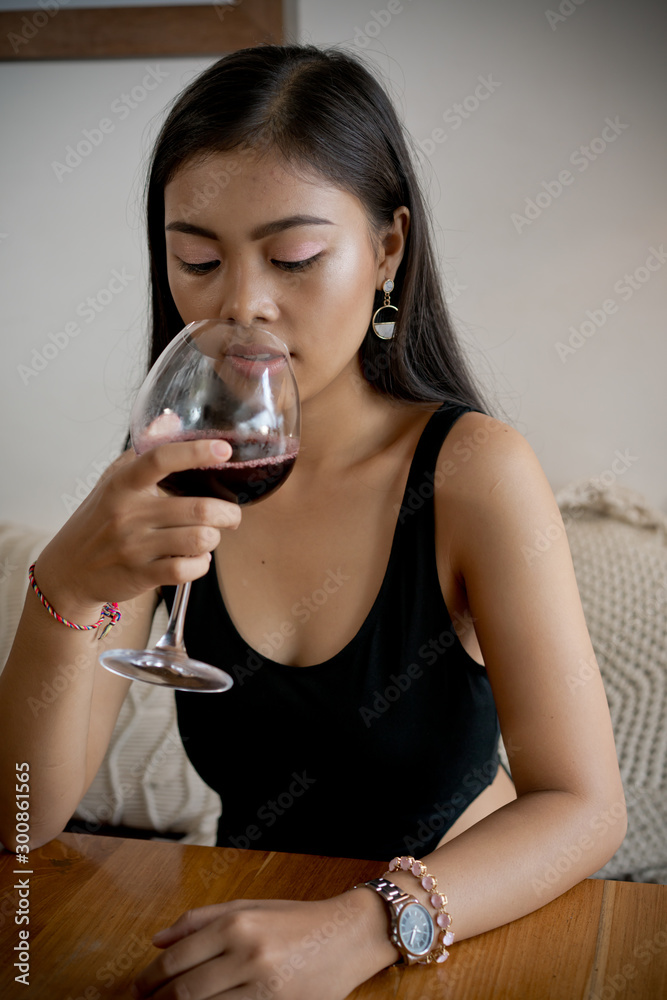 Asian girl in a cafe. Beautiful Balinese women with glass of wine with window reflection Asian girl in a cafe. Beautiful Balinese women with glass of wine with window reflection