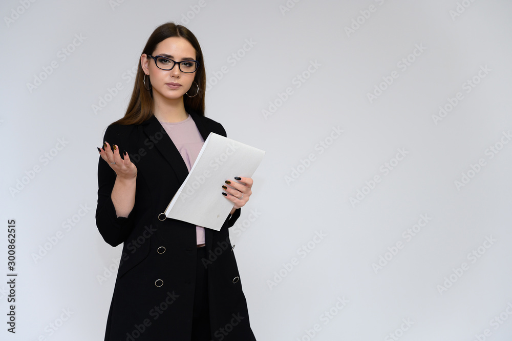 Close-up portrait of a young pretty girl secretary with long black hair in a black business suit, on a white background. Standing right in front of the camera in different poses with emotions. Close-up portrait of a young pretty girl secretary with long black hair in a black business suit, on a white background. Standing right in front of the camera in different poses with emotions.