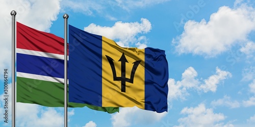 Gambia and Barbados flag waving in the wind against white cloudy blue sky together. Diplomacy concept, international relations.