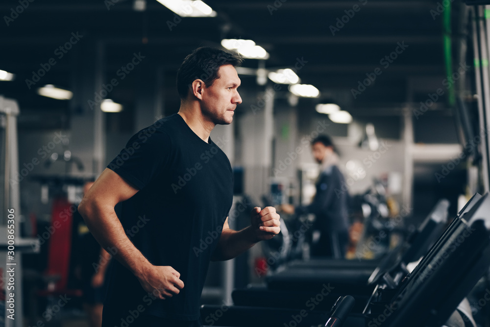 authentic image of attractive man running on the treadmill in the gym. concept of weight los and active living. authentic image of attractive man running on the treadmill in the gym. concept of weight los and active living.