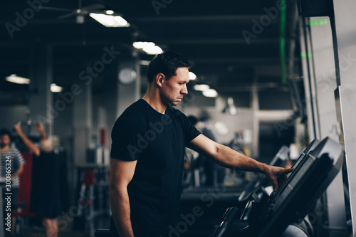 authentic image of attractive man running on the treadmill in the gym. concept of weight los and active living.