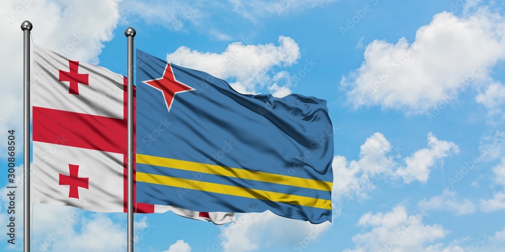 Georgia and Aruba flag waving in the wind against white cloudy blue sky together. Diplomacy concept, international relations.