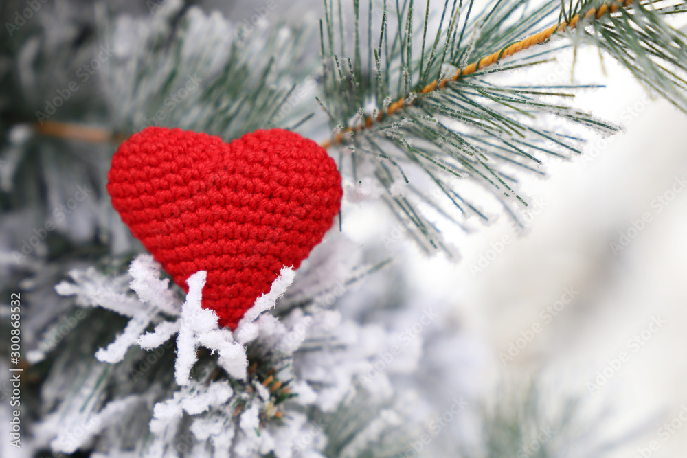 Christmas heart, red knitted symbol of love in the snow on fir branches. Background for romantic card, New Year celebration, Valentine's day or winter weather - obrazy, fototapety, plakaty 