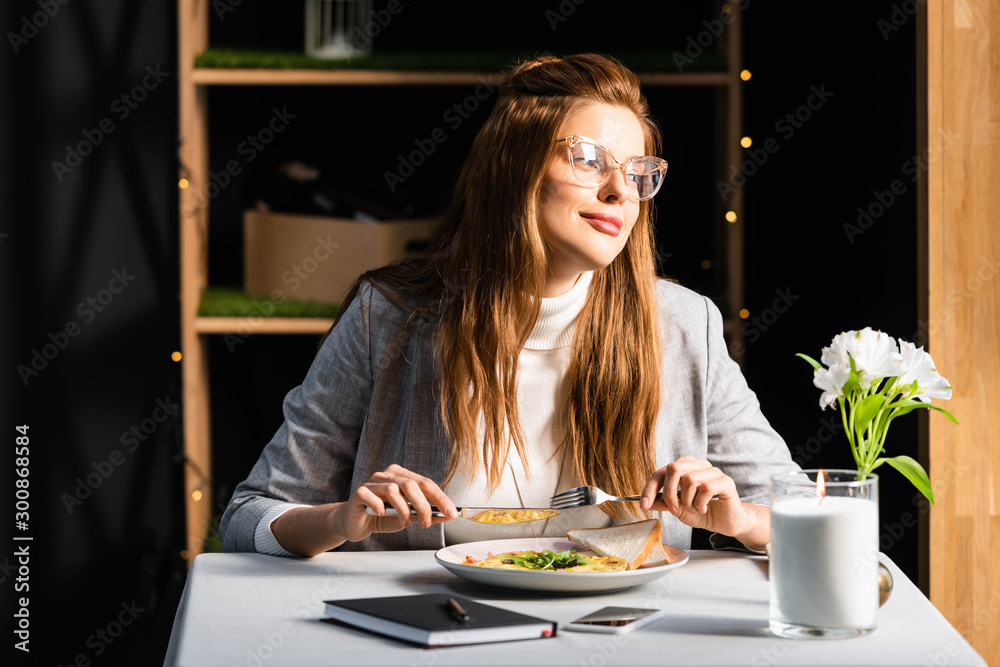 beautiful woman eating breakfast in cafe with notepad and smartphone
