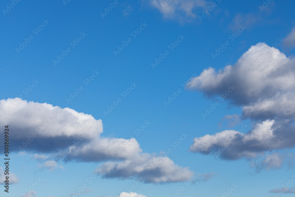 White, fluffy cloud float along the skyline over blue sky on a clear day. Background from clouds. - obrazy, fototapety, plakaty 