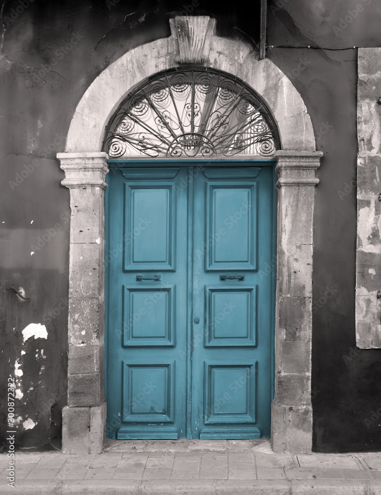 old blue door in an arched stone frame with flaking back painted walls