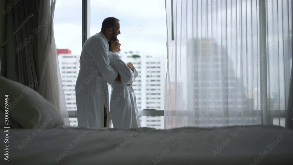 Young happy couple in love admire view from window at luxury home in the morning Young happy couple in love admire view from window at luxury home in the morning